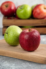 Whole wet green and red apples on wooden cutting board