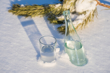 Glass bottle and glass of water on a white snow in winter