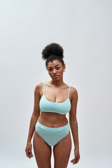Fototapeta premium Beautiful sexy young mixed race woman wearing blue underwear looking at camera while posing isolated over light background