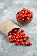 Red cherry tomatoes out of a rustic basket on marble background