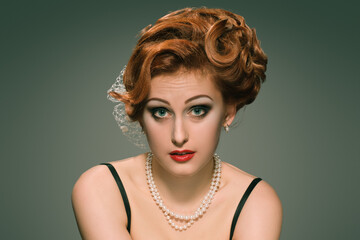 Gorgeous vintage model with confused facial expression wearing pearl necklace