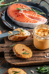 Homemade fish pate with herbs. Smoked salmon and soft cheese spread, mousse, pate in a jar with sliced bread. vertical image, place for text