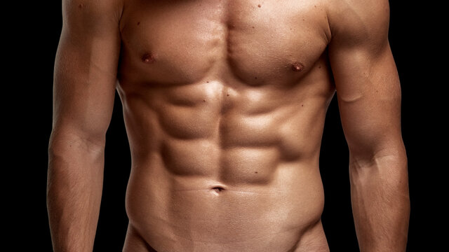 Closeup image of a strong athletic man showing muscular body and sixpack abs isolated black background.