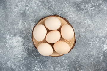 Pile of organic fresh uncooked eggs placed on wood piece