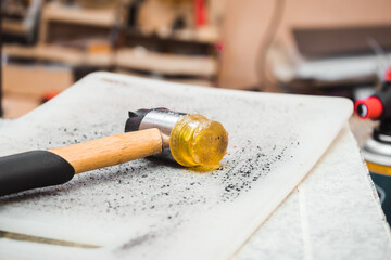 The hammer lies on a gray table with holes from blows