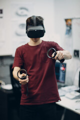 Young man in virtual reality goggles, vr glasses headset with joystick