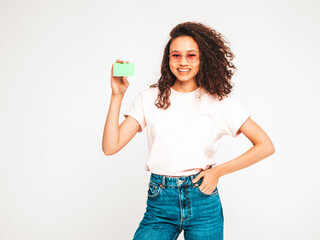 Beautiful black woman with afro curls hairstyle.Smiling model showing, presenting green credit card for making payment or paying online. Pay a merchant or as a cash advance for goods, Cardholder