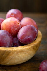 Ripe plums in a wooden bowl on the table.