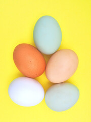 Chicken eggs of different colors on a yellow background. An ecological product. View from above.