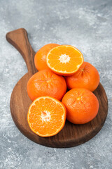 A wooden board full of juicy orange fruits on stone background