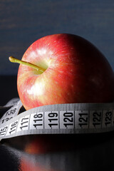 apple and tape measure on black background