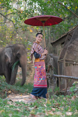 Beautiful Asian Woman wears thai dress with her elephant.