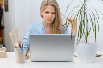 A girl with a laptop is studying at an online school. White room background