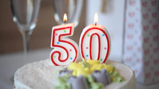 Birthday candle as number fifty 50 on top of sweet cake on the table, 50th birthday