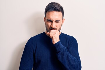 Young handsome man with beard wearing casual sweater standing over white background feeling unwell and coughing as symptom for cold or bronchitis. Health care concept.