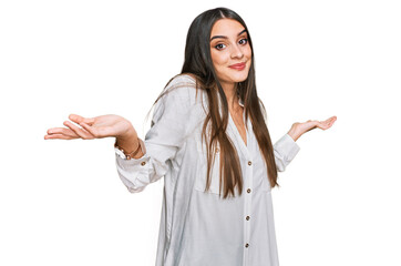 Young beautiful woman wearing casual white shirt clueless and confused expression with arms and...