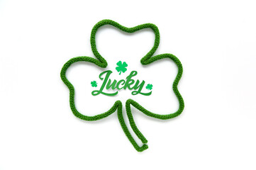 Lucky word - St. Patrick's day lettering. Brush calligraphy design with clover shamrock leaf. Greeting cards. Soft focus. Top view.