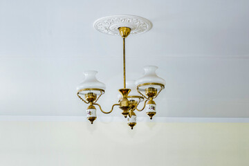 Classical retro chandelier white and golden colored hanging on ceiling.