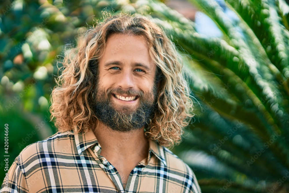 Wall mural young caucasian man with long hair smiling happy at the park.