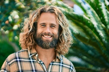 Young caucasian man with long hair smiling happy at the park.