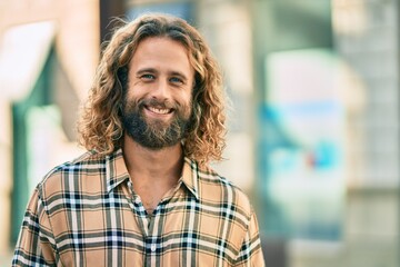 Young caucasian man with long hair smiling happy at the city.