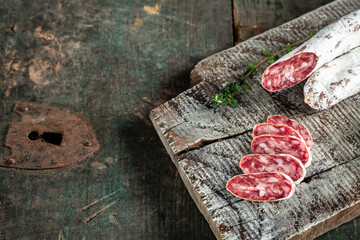 Spanish Fuet salami wurst with thyme on a wooden cutting board. menu recipe place for text, top view.