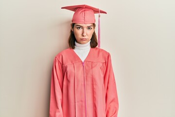 Young caucasian woman wearing graduation cap and ceremony robe depressed and worry for distress,...
