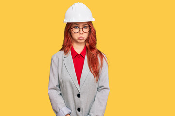 Young redhead woman wearing architect hardhat depressed and worry for distress, crying angry and afraid. sad expression.