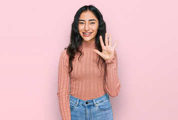 Hispanic teenager girl with dental braces wearing casual clothes showing and pointing up with...
