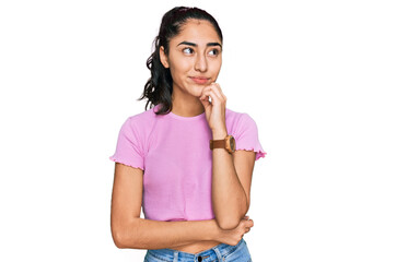 Hispanic teenager girl with dental braces wearing casual clothes with hand on chin thinking about question, pensive expression. smiling and thoughtful face. doubt concept.