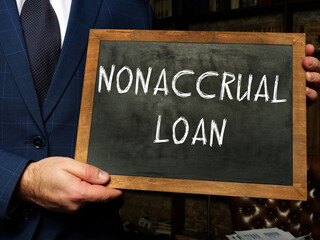  NONACCRUAL LOAN inscription on the screen. Businessman hands holding black smart phone.