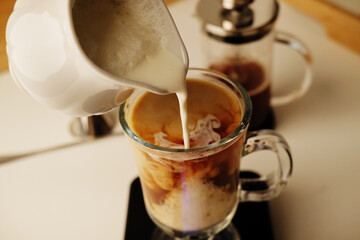 Milk coffee preparation process. Lightly whipped cream is poured into the coffee. Latte in irish glass