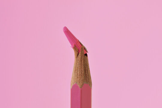 Close-up of broken tip of pink colored pencil on pink background - Concept of violence against women