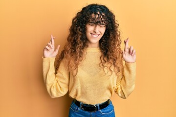 Young hispanic girl wearing casual clothes gesturing finger crossed smiling with hope and eyes closed. luck and superstitious concept.
