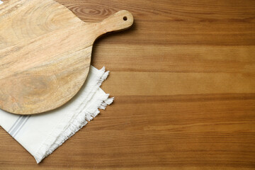 Empty wooden board and napkin on table, top view. Space for text
