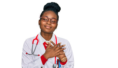 Young african american woman wearing doctor uniform and stethoscope smiling with hands on chest...