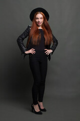 studio portrait of a young red-haired woman in black clothes on a black background