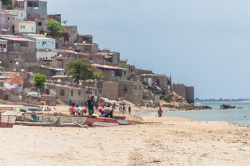 Beach view with fishermen and traditional Angolan boats, in Luanda beach, ghetto as background
