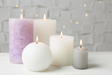 Fototapeta na wymiar Set of different candles burning on white table