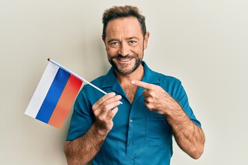 Middle age man holding russia flag smiling happy pointing with hand and finger