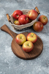 Pile of fresh ripe apples on wooden board and in basket
