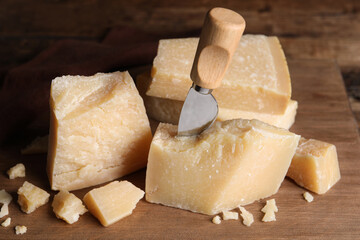 Parmesan cheese with knife on wooden board, closeup