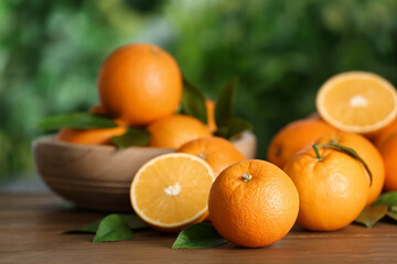 Fototapeta na wymiar Fresh ripe oranges on wooden table against blurred background. Space for text