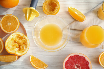 Freshly made juice, oranges and reamer on wooden table, flat lay