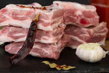 Raw pork ribs stacked with ingredients for cooking. Pepper, garlic, onion, tomato sauce and mustard.