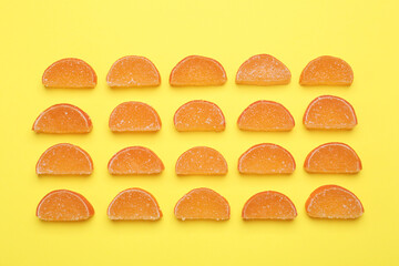 Delicious orange marmalade candies on yellow background, flat lay