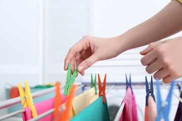 Woman hanging clean laundry on drying rack indoors, closeup