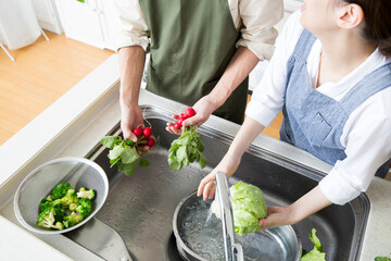 夫婦で料理　シンクで野菜を洗う