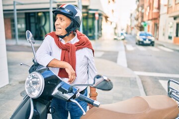 Obraz premium Senior motorcyclist man smiling happy wearing moto helmet at the city.