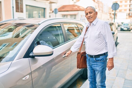 Senior man smiling happy opening car at the city.